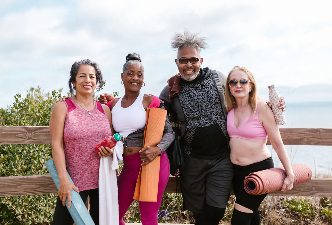 Quatre adultes sourient avec leurs tapis après une activité en plein air.